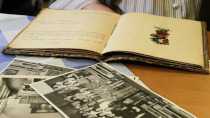 Libro abierto detrás de un montón de fotografías antiguas, sobre una mesa