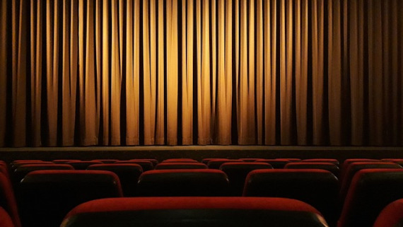 Escenario de un teatro visto desde el asiento de un espectador, con el telón bajado
