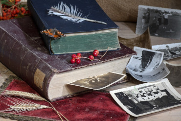 Libros abiertos amontonados con fotos antiguas asomando entre sus páginas